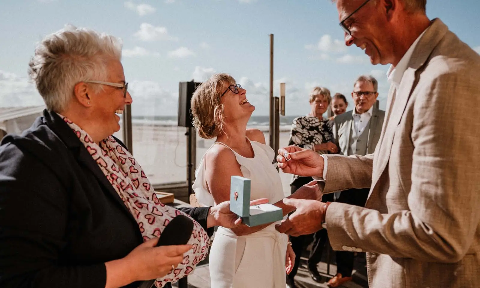 Eine Freie Trauung am Strand. Das Paar hat beim Ringtausch die Ringe verwechselt und lacht herzhaft.